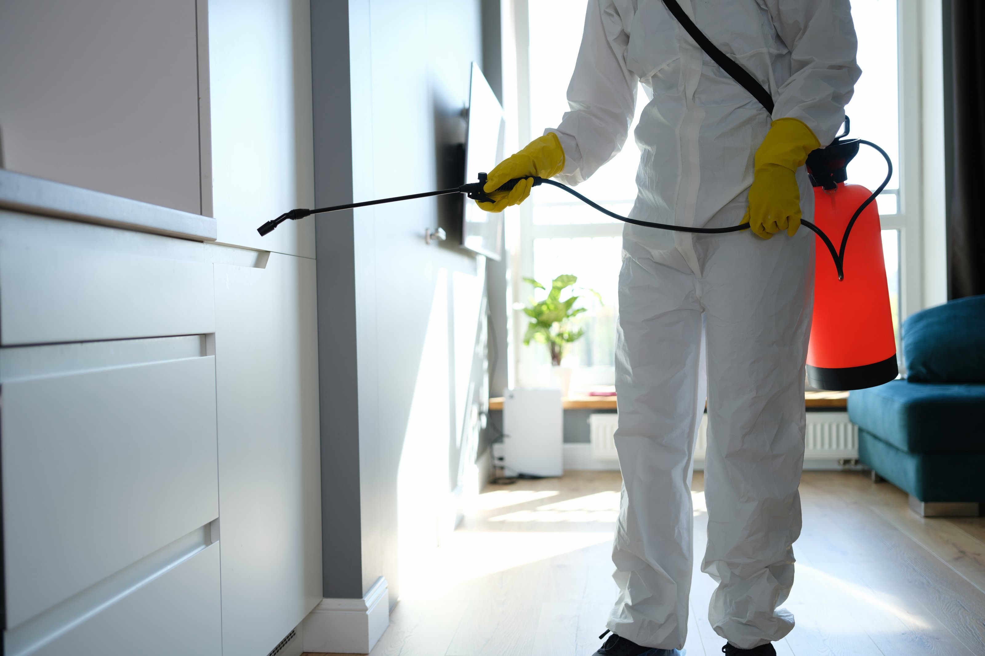 A Sevacorp technician in full protective gear treating a Pune home